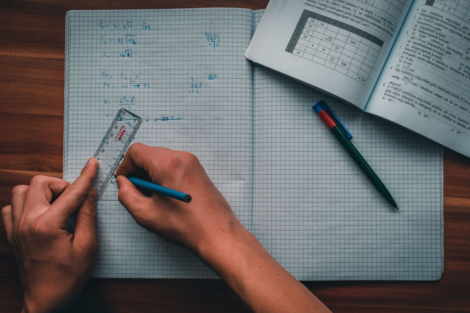 Aluno a resolver exercícios de geometria com régua e caderno quadriculado