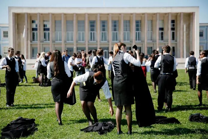 Grupo de caloiros com traje académico tradicional, em frente a um edifício universitário